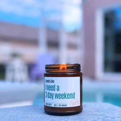 Candle with a label reading 'I need a 3 day weekend' by a poolside.