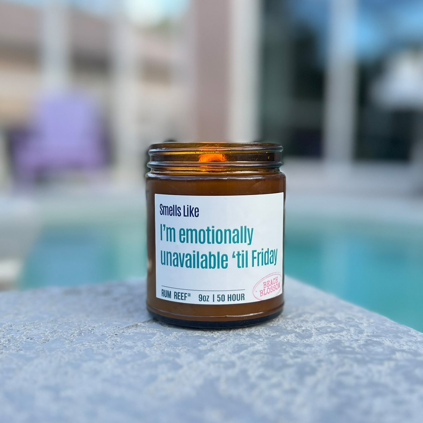 Candle in an amber jar with a humorous label by a poolside